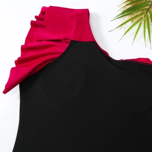Detailed close-up of one-shoulder swimsuit with vibrant pink ruffles on black fabric