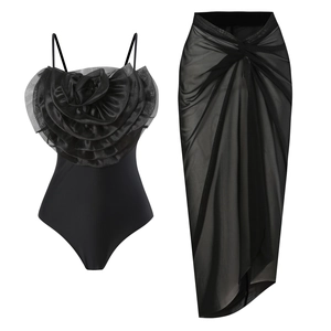 Detail of black one-piece swimsuit with 3D floral accent and matching mesh wrap skirt