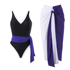 Flat lay of black and white one-piece swimsuit with a purple wrap beach skirt set