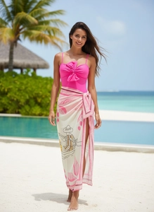 Pink bow one-piece swimsuit with tropical print wrap skirt on a sunny beach setting