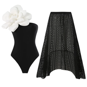 One-shoulder black swimsuit with white 3D floral accent and asymmetrical lace skirt set