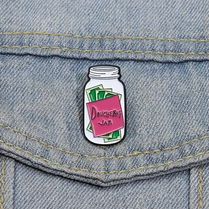 Gros plan sur le pin's émaillé Douchebag Jar attaché sur une veste en jean bleue
