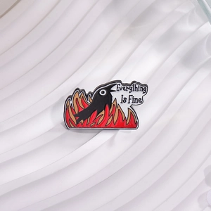 Black raven 'Everything Is Fine' enamel pin with red flames on white wavy tray