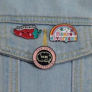 Three enamel pins on denim jacket showing red chili and rainbow neurodiversity designs