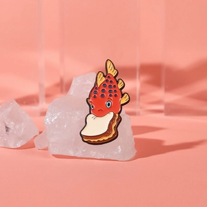 Detailed close-up of a red fish enamel pin holding a slice of bread on pink background