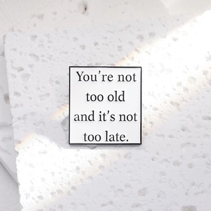 Minimalist square metal badge with inspirational quote on textured stone background