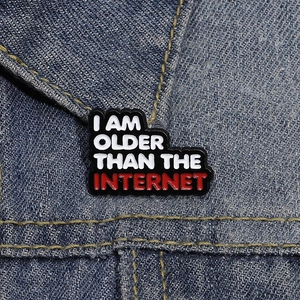 Macro shot of an enamel badge with I AM OLDER THAN THE INTERNET text on denim fabric