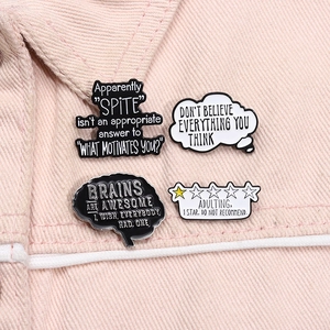 Set of four humorous black and white enamel brain pins on pink denim fabric background