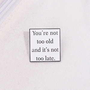 Macro shot of square enamel pin with motivational quote on off-white canvas
