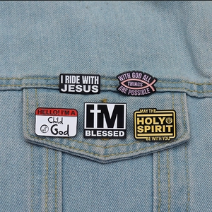 Detail of Christian enamel pins with religious quotes on a blue denim jacket pocket