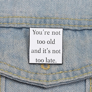 Close-up of inspirational square enamel pin on denim fabric with motivational quote