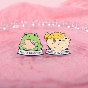 Cute cartoon animal enamel pins set featuring a frog and pufferfish with Not a Hugger banners