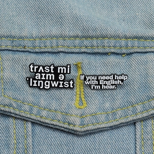 Close-up of enamel linguist pins with funny quotes on blue denim fabric background