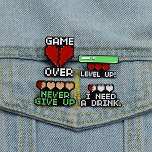 Detail of pixel art enamel pins with gaming motifs on a denim jacket pocket