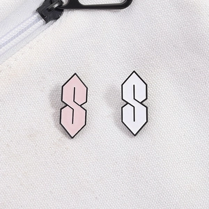 Close-up of pink and white Cool S enamel pins on white canvas bag with zipper detail
