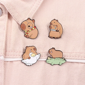 Detailed view of four cute capybara enamel pins on pink denim fabric background