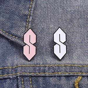 Detail of pink and white Cool S enamel pins on a denim jacket collar close-up