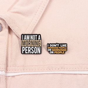 Macro detail of humoristic black enamel pins on a pink denim jacket with funny quotes
