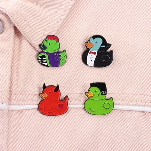 Macro detail of four Halloween horror duck enamel pins on pink denim fabric
