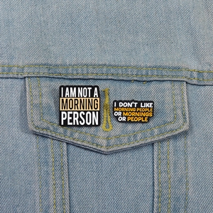 Detail of funny enamel morning pins attached to a blue denim jacket pocket