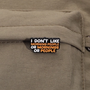 Detail of cynical enamel pin on canvas bag with I Don't Like Morning People quote