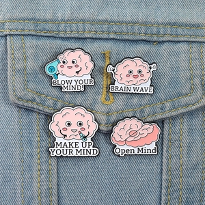 Détail de quatre broches cerveau en émail rose avec jeux de mots sur tissu denim