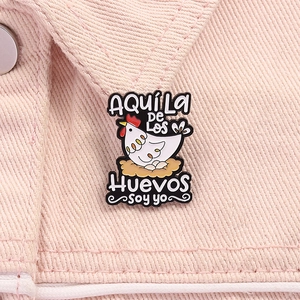 Detailed macro view of a cartoon hen enamel brooch with eggs on pink denim fabric