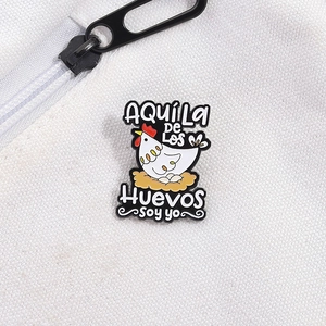 Cartoon enamel hen brooch pin with Spanish text on white canvas background