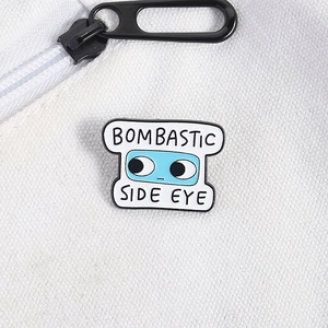 Macro detail of Bombastic Side Eye enamel pin with blue cartoon eyes on white fabric