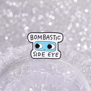 Bombastic Side Eye enamel pin with blue cartoon eyes and funny text on a glass edge