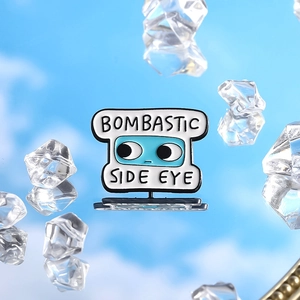 Macro view of blue Bombastic Side Eye enamel pin with ice cubes on reflective sky background