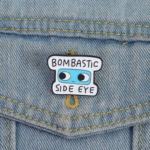 Detail of Bombastic Side Eye blue enamel badge pinned on light blue denim jacket pocket