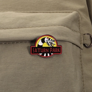Detail of a Saturn Park enamel pin featuring a striped snake on a beige canvas bag