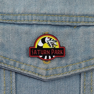 Saturn Park enamel pin featuring a black and white sandworm on a blue denim jacket