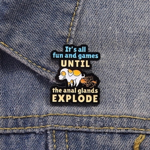 Gros plan du pin's émaillé chien drôle sur la texture d'une veste en jean