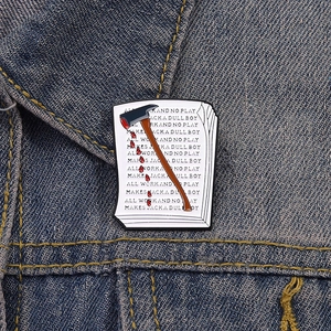 Gros plan du pin's émaillé The Shining montrant le manuscrit de Jack et une hache sanglante