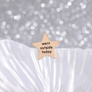 Gold star shaped enamel brooch featuring went outside today text on shell background