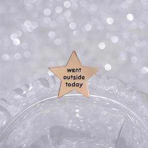 Golden star brooch featuring 'went outside today' lettering in a polished finish