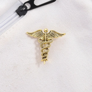 Macro detail of a vintage golden caduceus medical brooch with twin snakes and wings