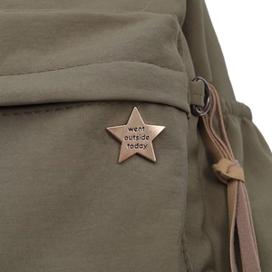 Detailed close-up of bronze star emblem and engraved text on olive green canvas bag