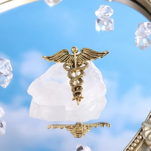 Detailed close-up of a vintage gold Caduceus medical brooch on a crystal stone base