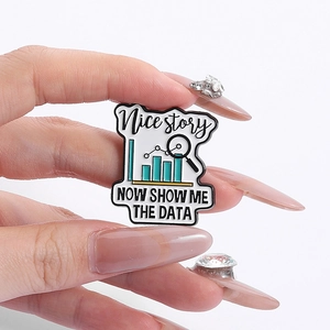 Macro detail of the Nice Story data analysis enamel pin held in hand for scale