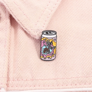 Detail of pink soda can enamel pin with 'Yes You Can' text on denim jacket fabric