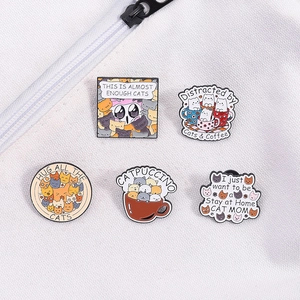 Flat lay of five cute cat enamel pins with coffee themes on a white canvas bag