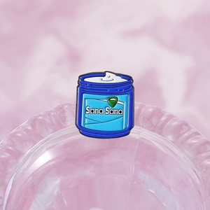 Blue enamel pin in ointment jar shape featuring Sana Sana text on a purple glass tray