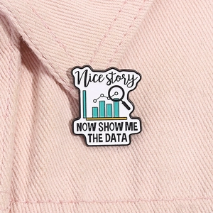 Detail of enamel data-themed brooch with magnifier and bar chart on pink denim jacket