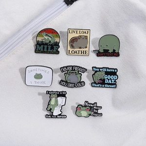 Eight-piece green enamel frog pins set with funny English slogans on white fabric background
