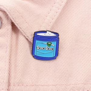 Macro shot of Sana Sana enamel pin showing blue cream jar design on pink denim texture