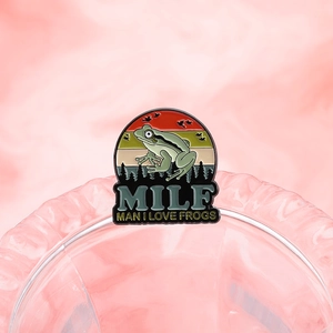 Cartoon frog enamel pin with MILF text on pink background for backpack and clothing accessories