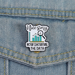 Macro detail of enamel pin with data charts and text on blue denim jacket